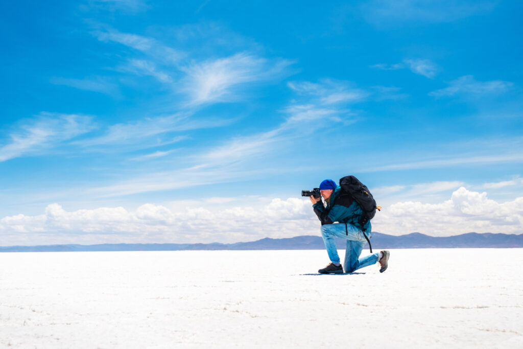 Photographer with tourist equipment taking photos in sunshine Salar de Uyuni